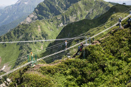 Russia Rosa Khutor-July 16, 2021: Tourist walks on the rope bridge.のeditorial素材