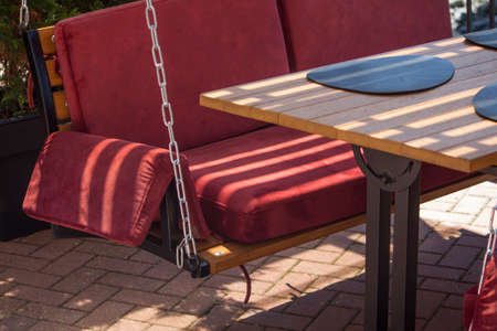 cozy red swing on chains instead of chairs in the outdoor restaurant of the resort town.