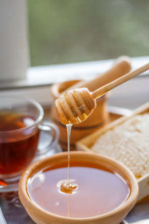 Honey in a bowl and in honeycombs still life by the windowの写真素材