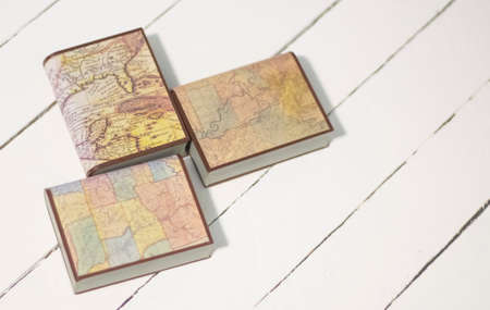 Encyclopedic books with maps of the world on a white wooden background with a copy of the spaceの写真素材