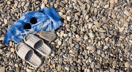 Black sunglasses, pareos and flip-flops on a pebble beach on a warm sunny day. The concept of summer holidays.の写真素材