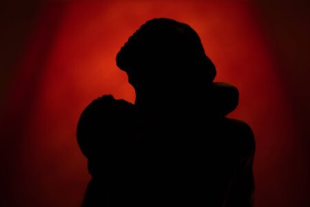 Silhouette love kiss statue Rodin the kiss red light background