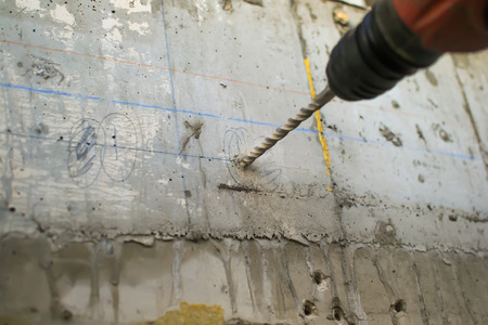 Drilling holes in the concrete wall on the building
