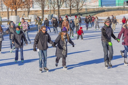 A couple skating, the woman is teaching her man how to skate perfectly in a cold winter day in the beautiful Skating Rink in Old Port of Montreal, Quebec ,Canadaのeditorial素材