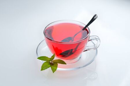 Hibiscus tea glass cup on a saucer with mint leaves and spoonの写真素材