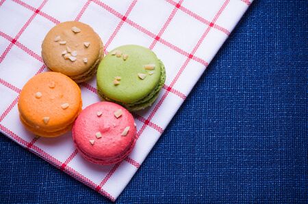 Macaroons put close together on blue table and white cloth with colorful and backlight.