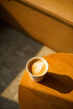 Coffee cup on wooden table in coffee shop, stock photo