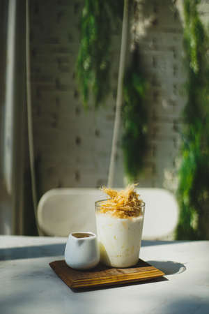 Dalgona coffee with whipped cream in a glass on a white tableの写真素材