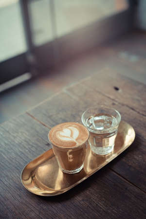 A cup of coffee with heart shape latte art on wooden tableの写真素材