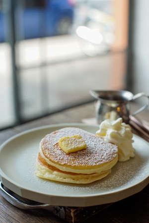 Pancakes with butter and sugar on a plate in a cafe