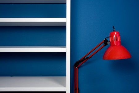 White empty bookcase with red reading lamp in blue roomの写真素材