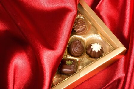 Golden chocolates box on red satin backgroundの写真素材
