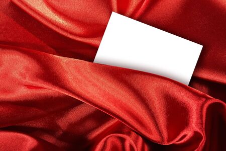 Blank white card on red colored satin clothの写真素材