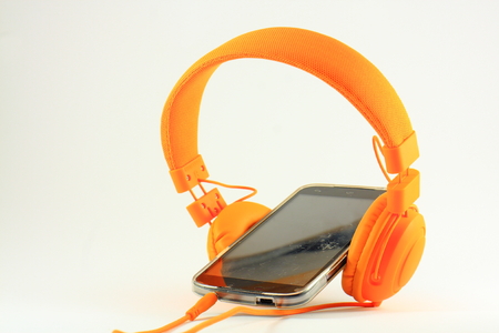 Orange headphones and mobile phone with a scratched screenの写真素材