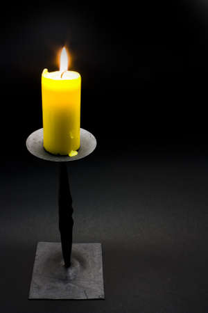 Yellow candle in front of black backgroundの写真素材