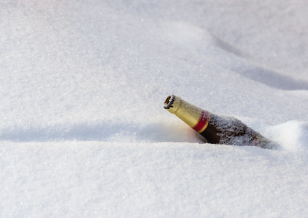 Empty bottle of dark glass on pure white snowの写真素材