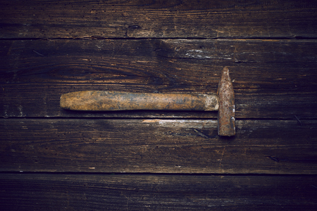 Old steel hammer with wooden handle on the wooden boards backgroundの写真素材