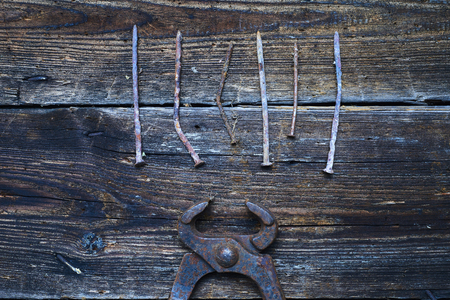 Old rusty tongs with nails on wooden boards backgroundの写真素材