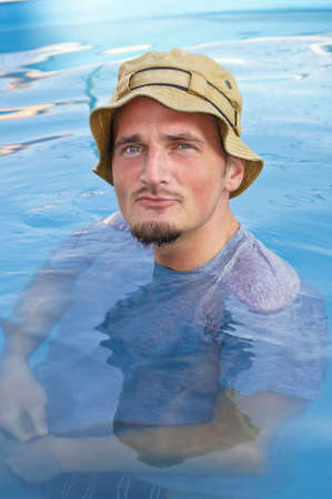 Young man with a hat on her head posing in waterの写真素材