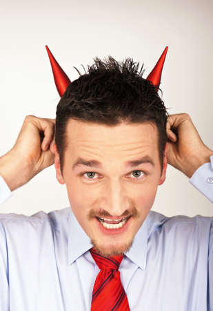 A young man shows horns on its headの写真素材