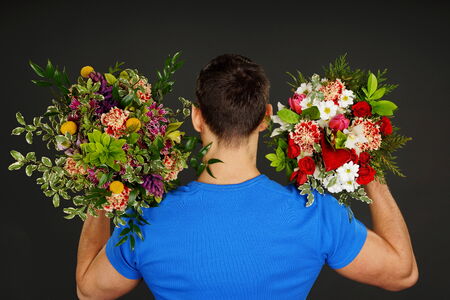 Man in blue shirt holds two beautiful bouquet flowers