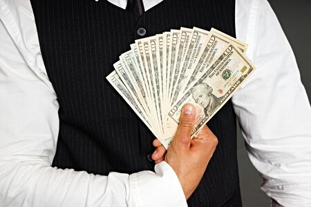 Businessman in black a vest holds a paper dollar bills