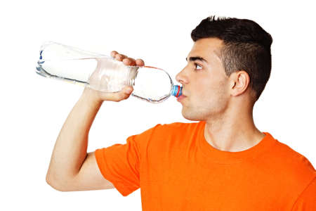 Young man in orange shirt drinks water from bottleの写真素材