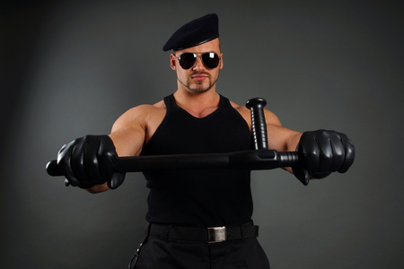 Muscular soldier in leather gloves holds nightstickの写真素材