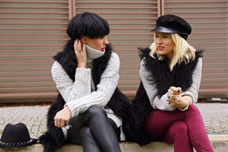 Two young attractive woman talks together outdoorの写真素材