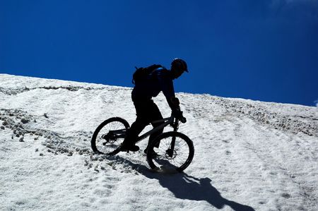 Sky, snow and mountain biker - downhill from mountain passの写真素材