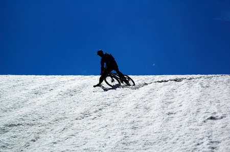 Sky, snow and mountain biker - downhill from mountain passの写真素材