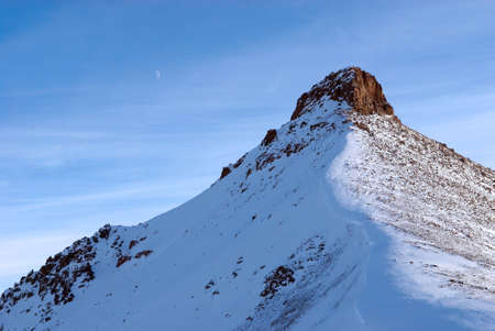 Mountain peak and moon in sundown sun lightの写真素材