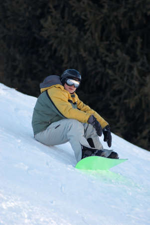 Snowboarder sits on ski slope の写真素材
