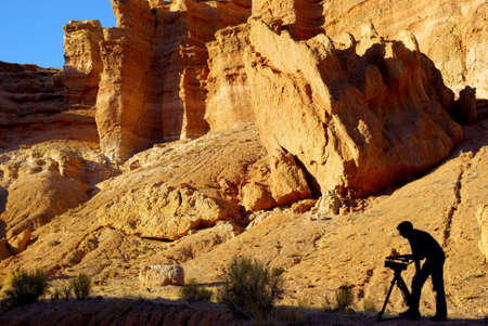 silhouette of man with video camera in canyonの写真素材