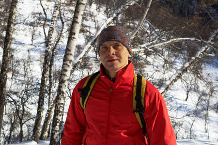 Backpacker in red in winter mountain forest