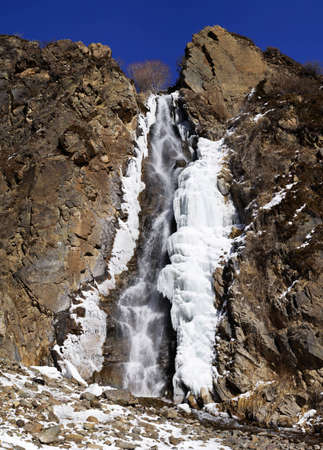 Waterfall, ice, rock and blue sky (vertical assembly of the two images)の写真素材