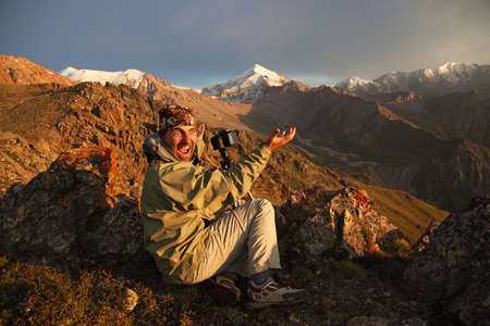 Photographer in the mountains at sunsetの写真素材
