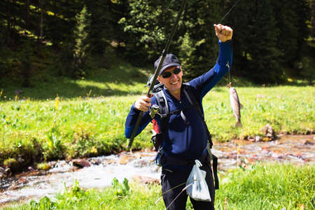 A fisherman shows catch trout in a mountain creek