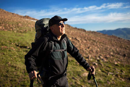 Adult backpacker admiring the sunrise in the mountainsの写真素材