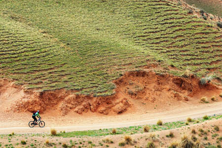 Mountain biker on rural road in desert mountains, Kazakstanの写真素材