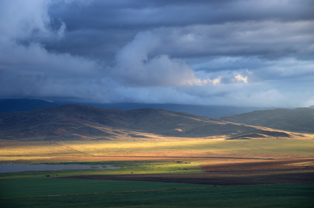 Storm sky and sun gaps on the fields and hills on the horizonの写真素材