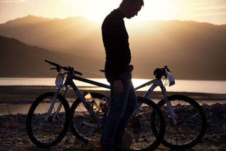 ALMATY, KAZAKSTAN - MAY 02, 2014: Silhouette of an athlete, who is preparing bike for the next day competition at Adventure mountain bike cross-country marathon in mountains "Jeyran Trophy 2014" のeditorial素材