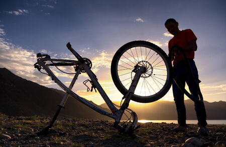 ALMATY, KAZAKSTAN - MAY 02, 2014: Silhouette of an athlete, who is preparing bike for the next day competition at Adventure mountain bike cross-country marathon in mountains "Jeyran Trophy 2014" のeditorial素材