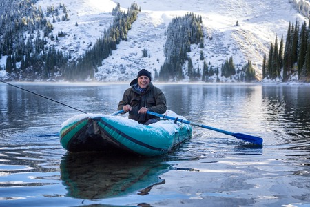 Autumn fishing after snowfall on the lake Kolsai, Kazakhstan