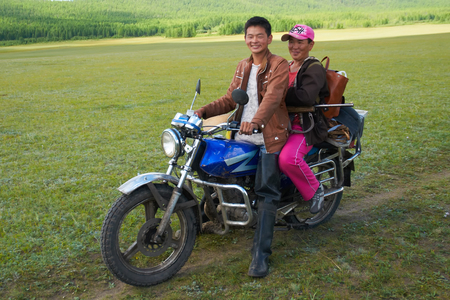 NORTHERN MONGOLIA , MONGOLIA - AUG 13, 2011: Mongol traveling with his wife on a motorcycle, stopped to talk with foreign tourists.のeditorial素材