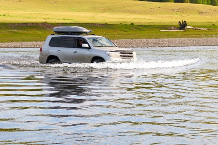 NORTHERN MONGOLIA, MONGOLIA - AUG 14, 2011: Foreign tourists in cars crossing Uur river  in northern Mongolia.のeditorial素材