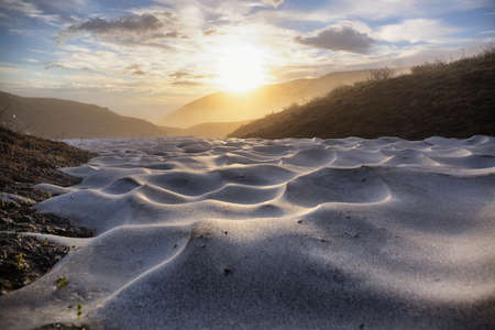 Sunrise over snowfield in summer highlands