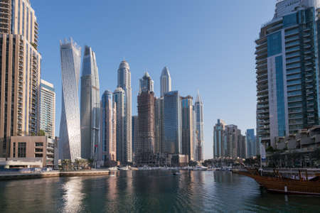 Dubai, UAE - 11.03.2017: Skyline of Dubai Marina on a hot day with clear sky. Skyscrapers, bay, boats, people walking by the water.のeditorial素材