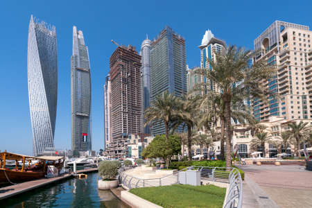 Dubai, UAE - 11.03.2017: Skyline of Dubai Marina on a hot day with clear sky. Skyscrapers, bay, boats, people walking by the water.のeditorial素材