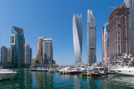 Dubai, UAE - 11.03.2017: Skyline of Dubai Marina on a hot day with clear sky. Skyscrapers, bay, boats, people walking by the water.のeditorial素材